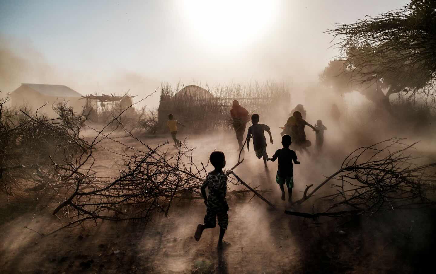 Children and women run among a cloud of dust at the village of El Gel, eight kilometres from the town of K’elafo, Ethiopia, on January 12, 2023. The last five rainy seasons since the end of 2020 have failed, triggering the worst drought in four decades in Ethiopia, Somalia, and Kenya. According to the UN, drought has plunged 12 million people into “acute food insecurity” in Ethiopia alone.